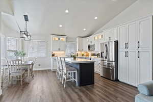 Kitchen featuring lofted ceiling, stainless steel appliances, a kitchen island, and light countertops