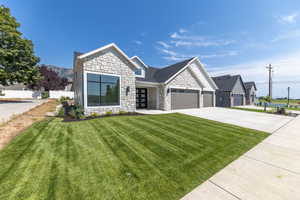 View of front facade with stone siding, board and batten siding, an attached garage, and concrete driveway