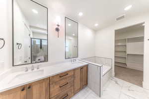Primary Bathroom featuring double vanity, recessed lighting, a bath, marble finish floors, and a walk in closet