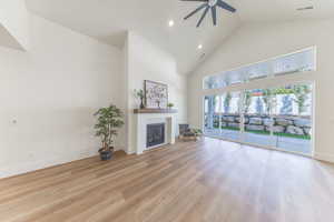 Unfurnished living room with high vaulted ceiling, ceiling fan, a fireplace, wood finished floors, and recessed lighting