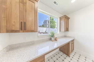 Kitchen with light floors, light stone counters, and brown cabinetry