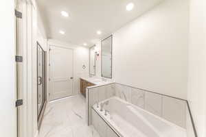 Primary Full bath featuring marble look tiles, recessed lighting, a garden tub, and double vanity