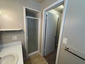 Bathroom featuring baseboards, a stall shower, and a sink