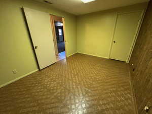 Empty room with baseboards, visible vents, and tile patterned floors