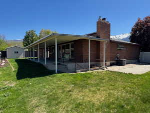 Back of property with brick siding, a mountain view, a yard, a patio, and a chimney