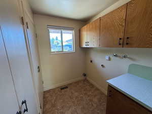 Clothes washing area featuring cabinet space, hookup for an electric dryer, hookup for a washing machine, visible vents, and baseboards
