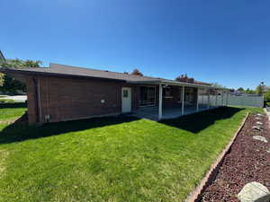 Rear view of house with a chimney, fence, a yard, brick siding, and a patio area