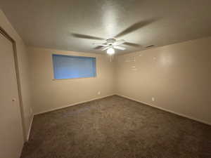Unfurnished room featuring ceiling fan, a textured ceiling, baseboards, and dark carpet