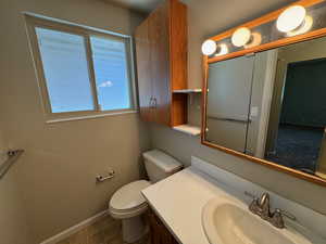 Bathroom with baseboards, tile patterned flooring, vanity, and toilet