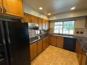 Kitchen featuring brown cabinets, tasteful backsplash, black appliances, and a sink