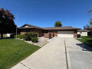 Ranch-style house featuring an attached garage, brick siding, driveway, and a front lawn