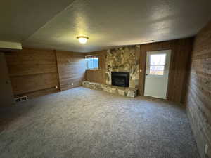 Unfurnished living room featuring wooden walls, a textured ceiling, and plenty of natural light