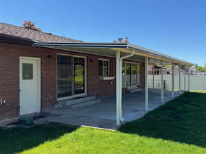 Back of property featuring a patio, fence, a yard, brick siding, and entry steps