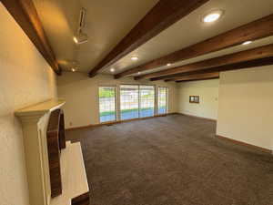 Unfurnished living room with carpet flooring, baseboards, and a textured wall