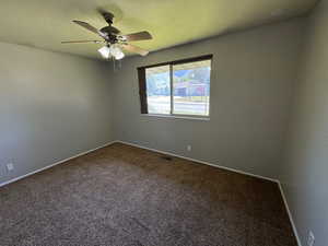 Carpeted empty room featuring baseboards, a ceiling fan, and visible vents