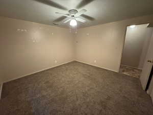 Carpeted empty room featuring visible vents, baseboards, and ceiling fan