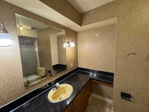 Bathroom with toilet, a shower with door, tile patterned flooring, and vanity
