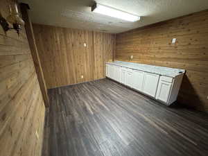 Spare room with dark wood-style floors, wooden walls, and a textured ceiling