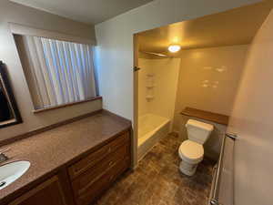 Bathroom featuring shower / bathing tub combination, vanity, toilet, and stone finish floor