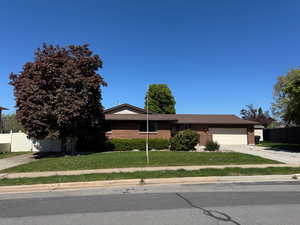 View of front facade with fence, brick siding, concrete driveway, a garage, and a front yard