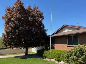 View of side of home featuring roof with shingles, brick siding, and fence
