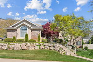 Exterior space with brick siding, fence, a front yard, and stairs