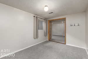 Unfurnished bedroom featuring carpet flooring, a textured ceiling, visible vents, and baseboards