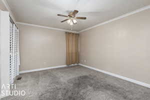 Empty room with ornamental molding, visible vents, ceiling fan, and carpet