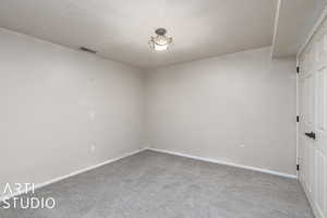 Unfurnished room with baseboards, carpet flooring, visible vents, and a textured ceiling