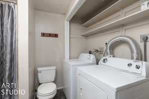 Clothes washing area featuring baseboards, separate washer and dryer, laundry area, and a textured ceiling
