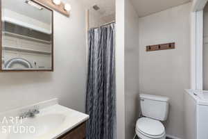 Full bath with toilet, a shower with shower curtain, a textured ceiling, vanity, and washer / clothes dryer