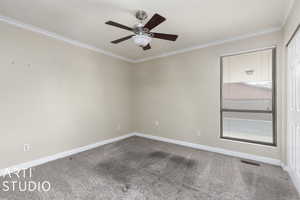 Carpeted spare room with ceiling fan, ornamental molding, baseboards, and visible vents