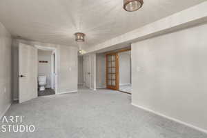 Interior space featuring a textured ceiling, connected bathroom, carpet floors, and baseboards
