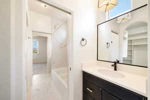 Full bathroom featuring marble finish floor, vanity, and plenty of natural light