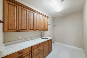Washroom with baseboards, visible vents, washer hookup, a sink, and cabinet space