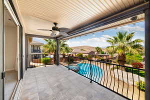 Balcony with a mountain view, a pool with connected hot tub, and a ceiling fan