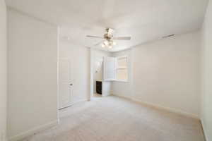 Spare room with light colored carpet, baseboards, a ceiling fan, and visible vents