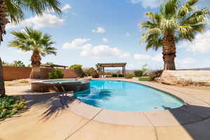 View of pool with a patio, a pool with connected hot tub, a pergola, and a fenced backyard