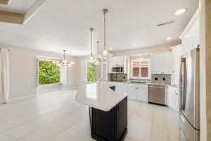 Kitchen featuring white cabinetry, decorative backsplash, visible vents, and appliances with stainless steel finishes
