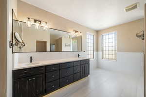 Full bathroom featuring wainscoting, double vanity, and a sink