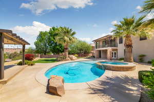 View of swimming pool with a patio, a pool with connected hot tub, and a fenced backyard