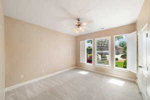Carpeted empty room featuring baseboards, a ceiling fan, and visible vents