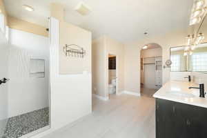Full bath featuring a sink, double vanity, walk in shower, and toilet