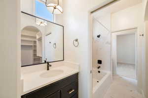 Bathroom with marble finish floor, vanity, and washtub / shower combination