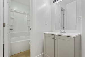 Full bathroom with vanity, wood finished floors, toilet, and shower / washtub combination