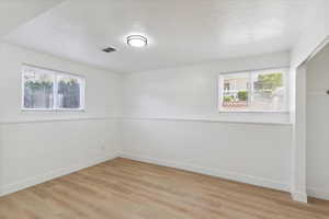 Spare room with visible vents, a textured ceiling, light wood-style floors, and a wealth of natural light