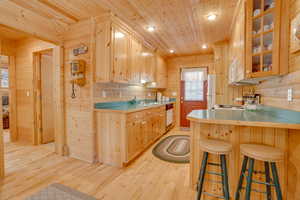 Kitchen featuring white appliances, wooden walls, light wood-style flooring, and wooden ceiling