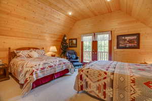 Carpeted bedroom featuring vaulted ceiling, wood walls, wood ceiling, and access to outside