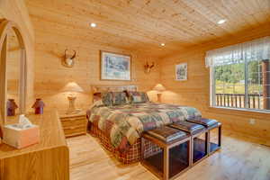 Bedroom with recessed lighting, wood ceiling, visible vents, and wooden walls