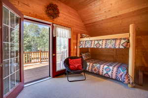 Bedroom with access to exterior, wood walls, lofted ceiling, and carpet floors